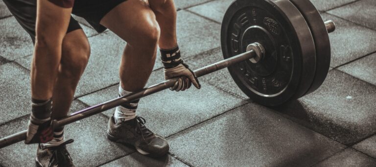 Mann beim Gewichtheben im Fitnessstudio: Eine Langhantel mit schweren Gewichten wird für ein Krafttraining angehoben